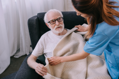 Caregiver covering senior patient with plaid